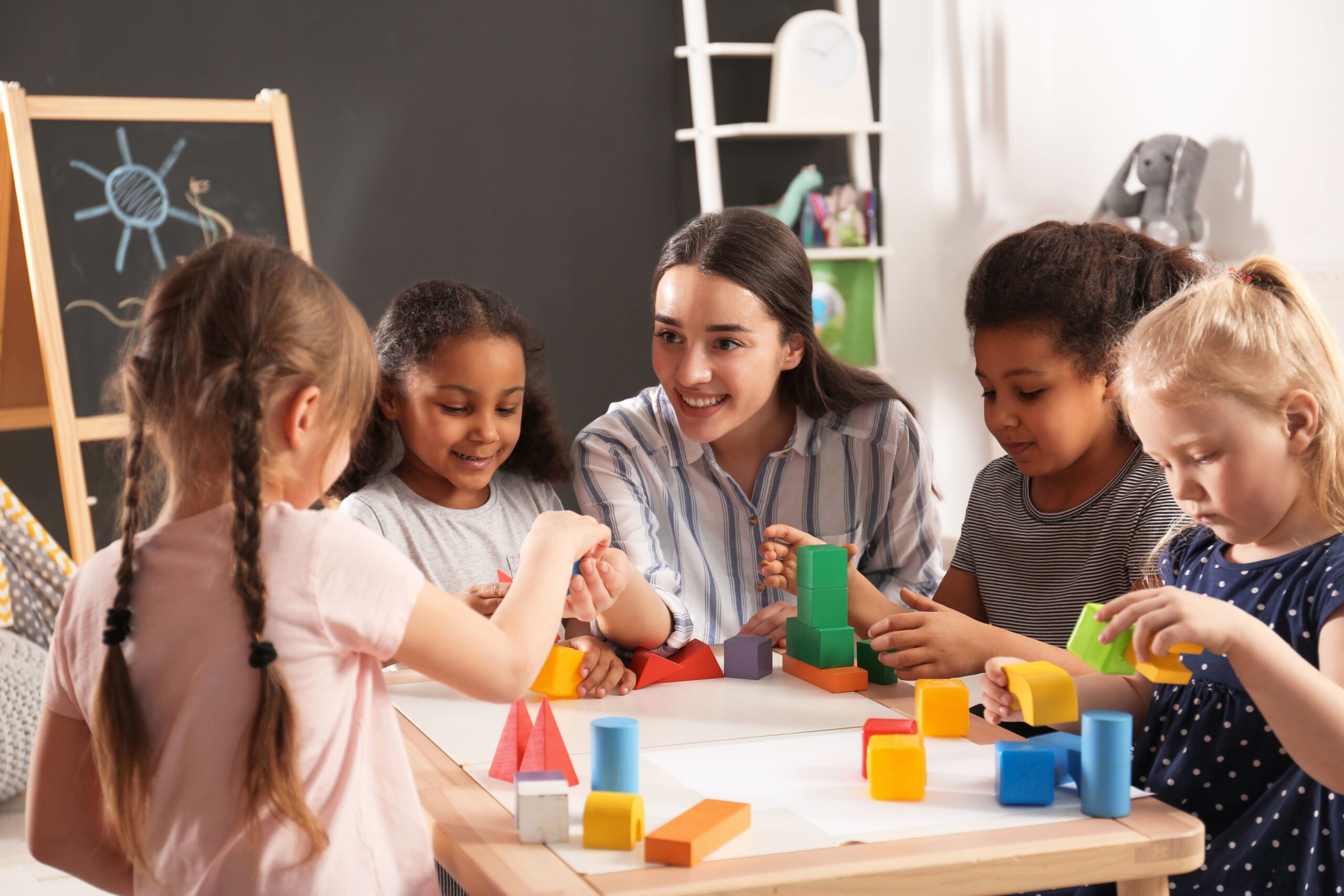 1 adult and 4 children sitting around a table playing with building blocks